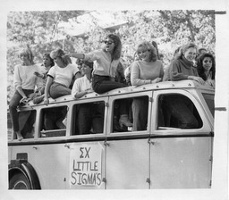 Members of a sorority ride in a van in a Homecoming parade